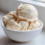 Close-up of three scoops of thick, creamy vanilla protein smoothie bowl mixture in a white bowl.