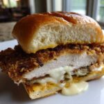 Cross-section view of a Crispy Chicken Burger with Melty Cheese showing the thick, golden-brown fried chicken patty and oozing white cheese.