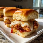 Close-up of a Crispy Chicken Parmesan Slider with melted mozzarella cheese dripping over the breaded chicken and marinara sauce.