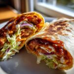 Close-up of a Crispy Chicken Wrap with Honey Garlic Sauce cut in half, showing crispy chicken, slaw, and sauces.