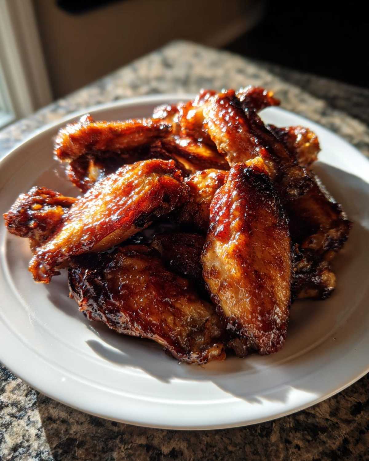 A plate piled high with glossy, crispy Honey Garlic Chicken Wings baked to a perfect golden-brown.