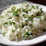 A close-up of fluffy Cilantro Lime Rice for Burrito Bowls, featuring bright white grains mixed with chopped green cilantro.