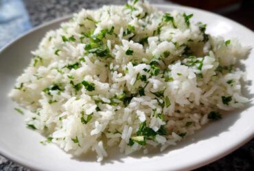 A close-up of fluffy Cilantro Lime Rice for Burrito Bowls, featuring bright white grains mixed with chopped green cilantro.