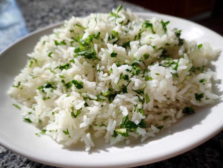 A close-up of fluffy Cilantro Lime Rice for Burrito Bowls, featuring bright white grains mixed with chopped green cilantro.