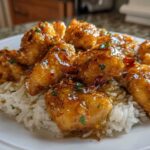 Close-up of golden Garlic Butter Chicken Bites coated in a shiny glaze, served over a bed of white rice.
