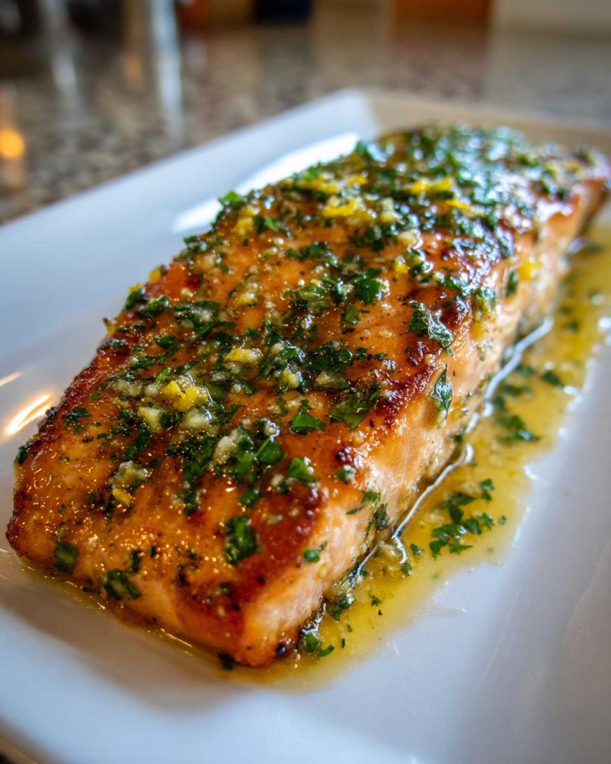 Close-up of a perfectly cooked fillet of Garlic Butter Salmon with Lemon Herb Sauce drizzled over top.