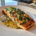 A perfectly cooked fillet of Garlic Butter Salmon with Lemon Herb Sauce, glistening with butter and topped with fresh parsley.