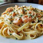 Close-up of creamy Garlic Butter Shrimp Alfredo Pasta with fettuccine noodles and pink shrimp, garnished with parsley.