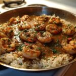 Close-up of Garlic Butter Shrimp and Rice Skillet cooking in a stainless steel pan, garnished with parsley.