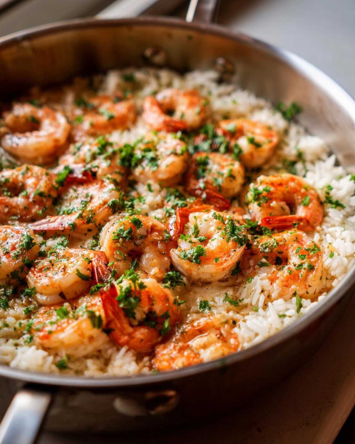 Close-up of Garlic Butter Shrimp and Rice Skillet topped with fresh parsley in a stainless steel pan.