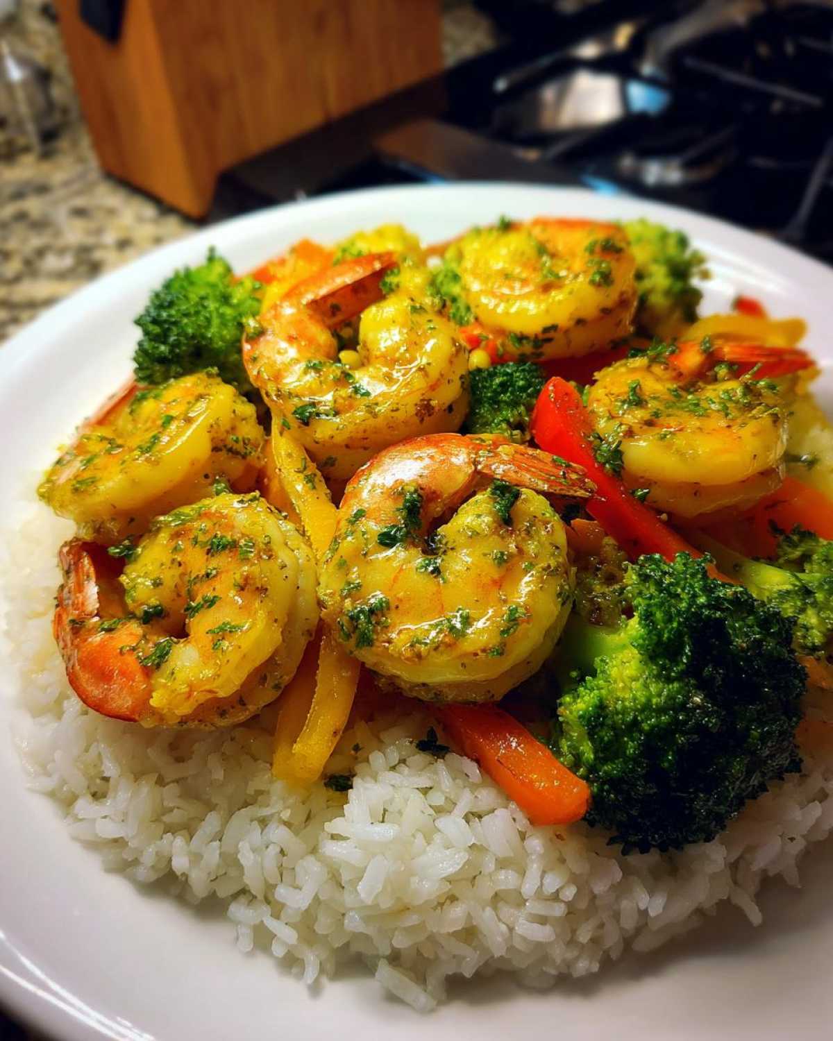 Close-up of Garlic Butter Shrimp with Rice and Veggies, featuring bright yellow shrimp over white rice and colorful steamed vegetables.