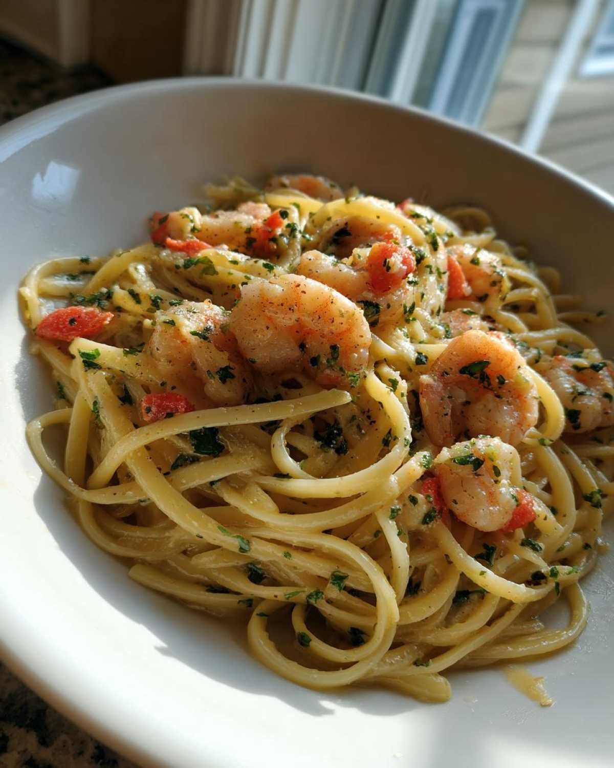 Close-up of Garlic Butter Shrimp with Pasta tossed in a creamy sauce and topped with parsley in a white bowl.