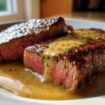 Two thick slices of perfectly cooked Garlic Butter Steak with Creamy Sauce, showing a medium-rare center.