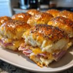Close-up of baked Hawaiian Roll Ham and Cheese Sliders topped with poppy seeds and a shiny glaze.
