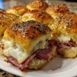 Close-up of baked Hawaiian Roll Ham and Cheese Sliders topped with poppy seeds and melted cheese.