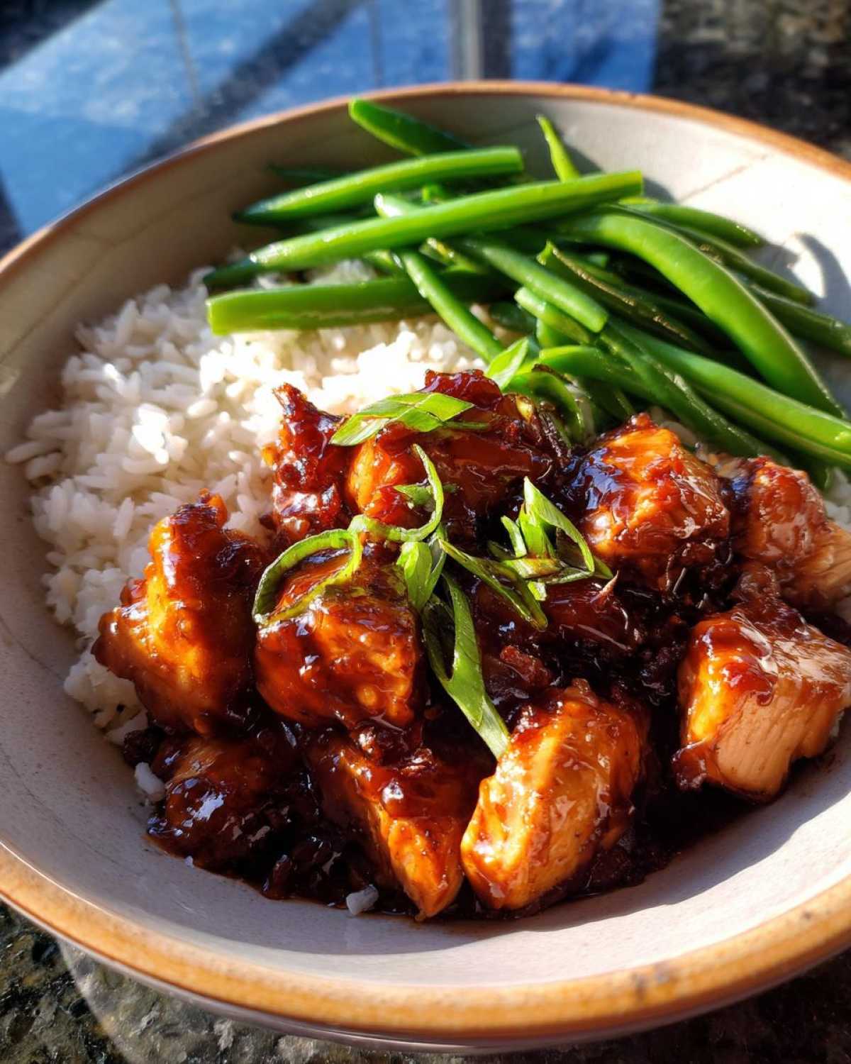 Close-up of a Honey Garlic Chicken Bowl featuring glazed chicken pieces over white rice with steamed green beans.