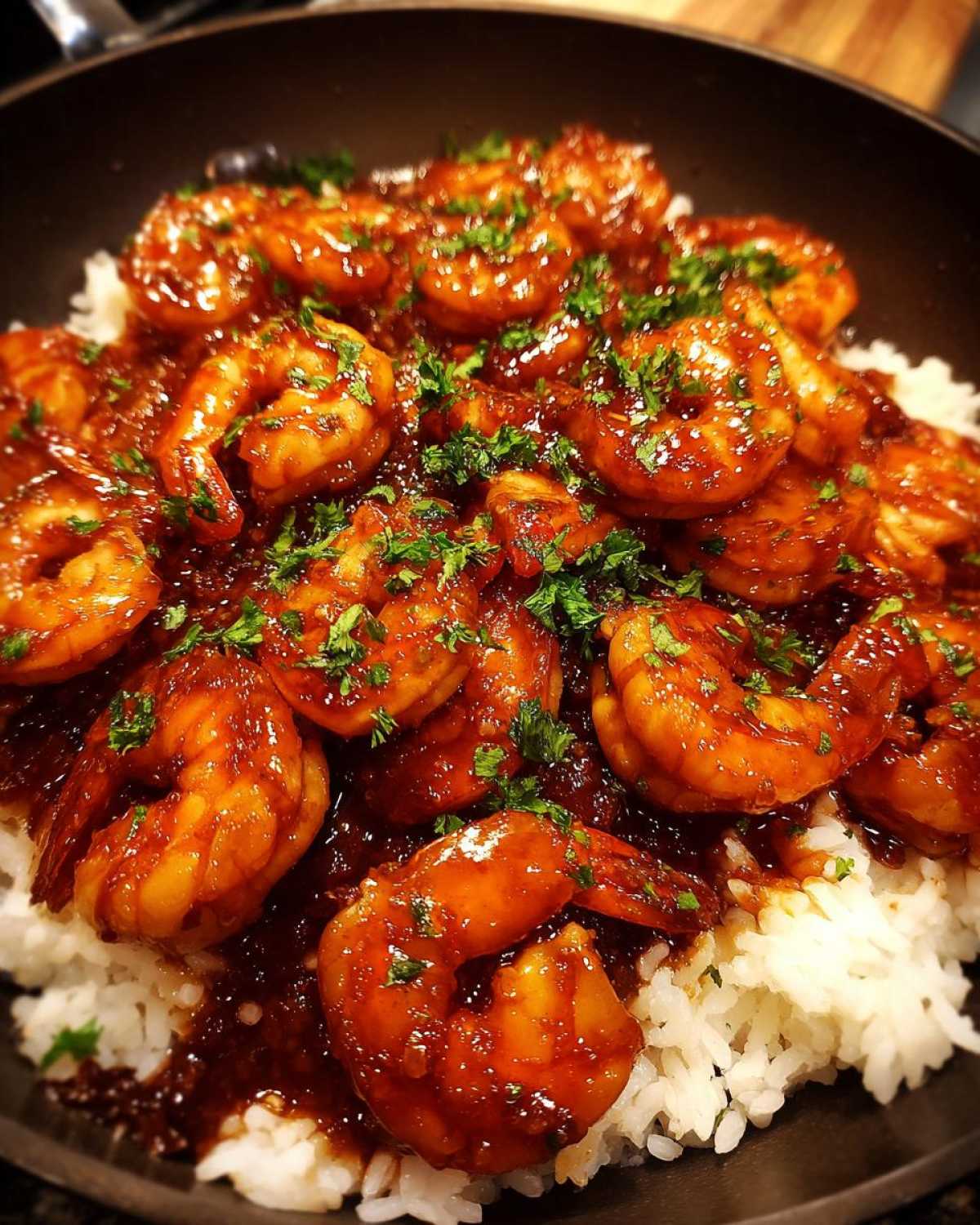 Close-up of Honey Garlic Shrimp Skillet with shrimp coated in a thick, glossy sauce served over white rice and garnished with parsley.