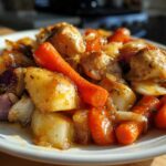 Close-up of a serving of Honey Mustard Chicken Bake with Veggies, featuring glazed chicken pieces, carrots, potatoes, and red onion.