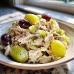 A bowl of creamy Honey Mustard Chicken Salad with Grapes and chopped celery, highlighted by natural light.