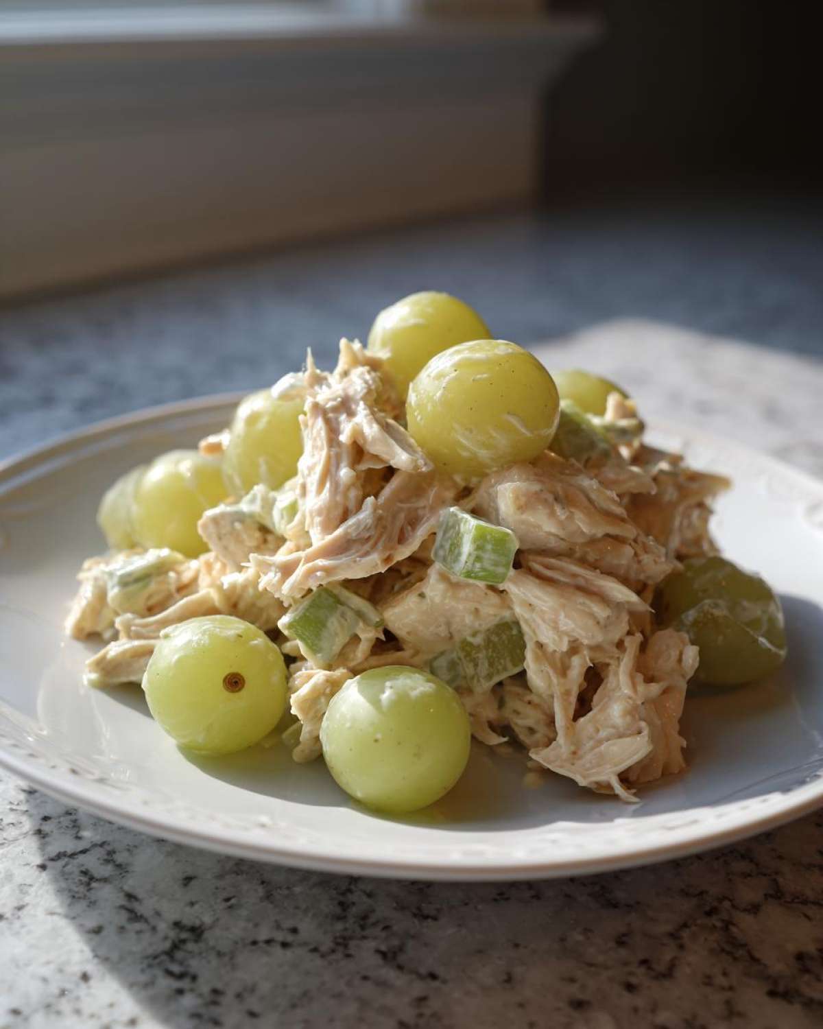 A serving of creamy Honey Mustard Chicken Salad with Grapes and celery chunks on a white plate.