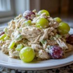 A mound of creamy Honey Mustard Chicken Salad with Grapes and celery served on a white plate.