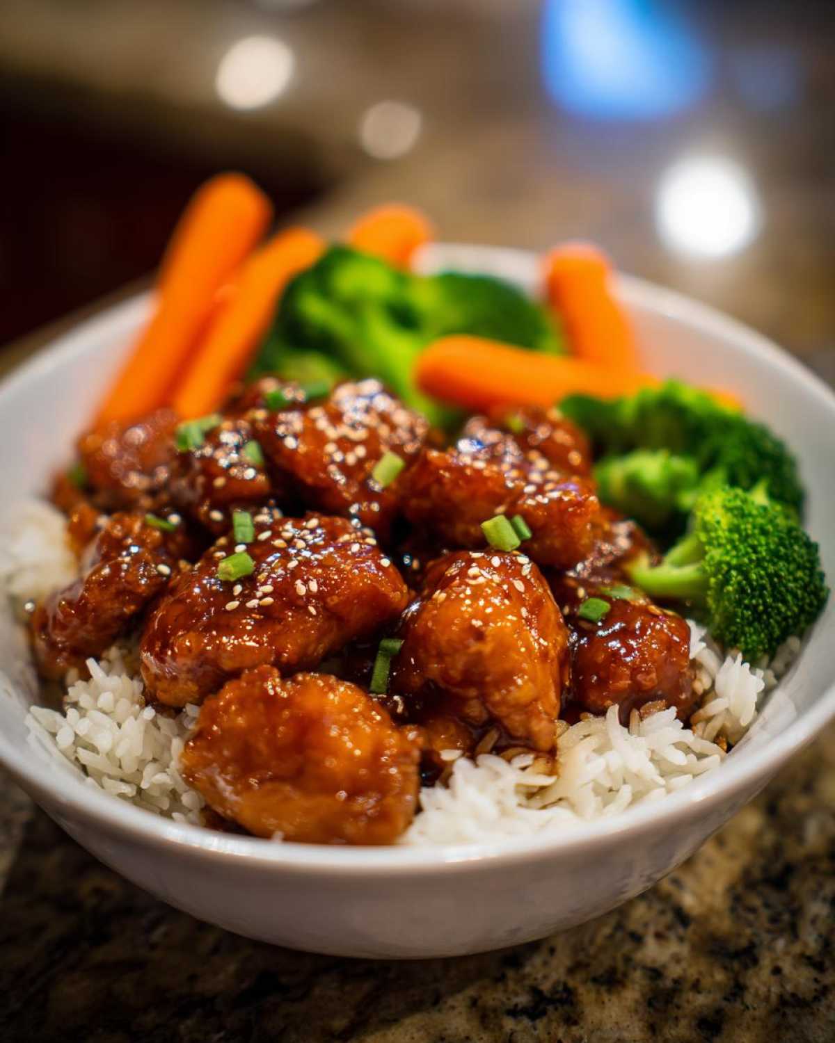 Close-up of a Honey Soy Chicken Bowl Quick Dinner Idea featuring glazed chicken pieces over white rice with steamed broccoli and carrots.