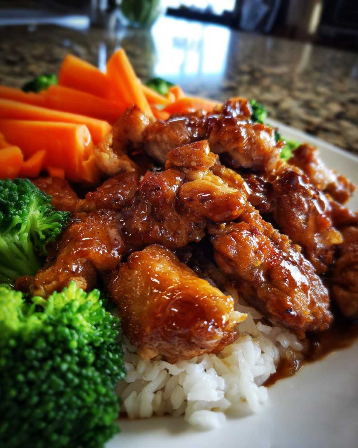 Close-up of Honey Soy Chicken Bowl Quick Dinner Idea featuring glazed chicken pieces over white rice with bright green broccoli and sliced carrots.