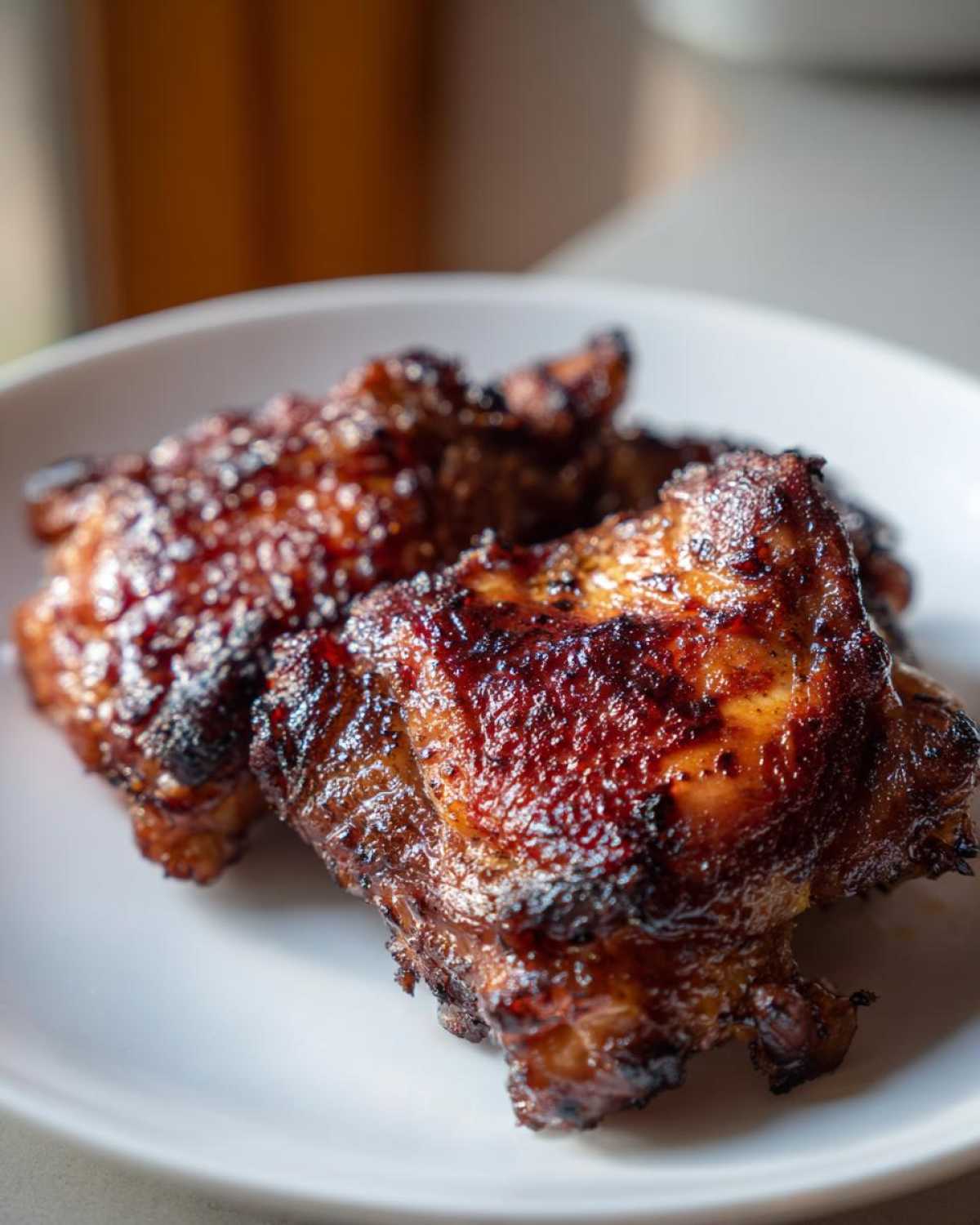 Close-up of perfectly cooked Honey Soy Chicken Thighs with crispy, caramelized edges on a white plate.