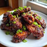 A close-up of glossy Honey Soy Chicken Wings Crispy Oven Baked, garnished with sesame seeds and green onions.