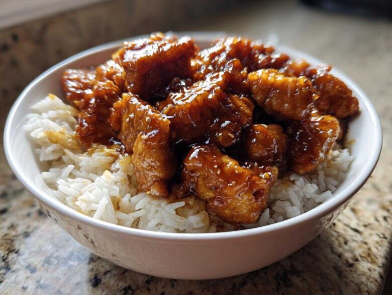 Close-up of crispy chicken pieces coated in glossy sauce served over white rice in a bowl, featuring Honey Soy Garlic Chicken.