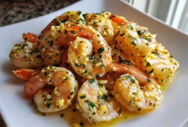 Close-up of succulent Lemon Butter Shrimp with Garlic Flavor, coated in butter sauce and fresh parsley, served on a white plate.