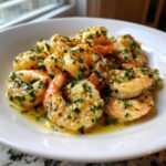 Close-up of succulent shrimp coated in a rich sauce with visible minced garlic and fresh parsley, representing Lemon Butter Shrimp with Garlic Flavor.