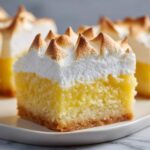 A single serving of Lemon Meringue Pie Bars featuring a thick, bright yellow lemon layer topped with perfectly piped and toasted meringue peaks.
