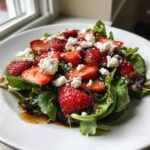 Close-up of a vibrant Spring Mix Salad with Strawberries and Goat Cheese, drizzled with balsamic glaze.