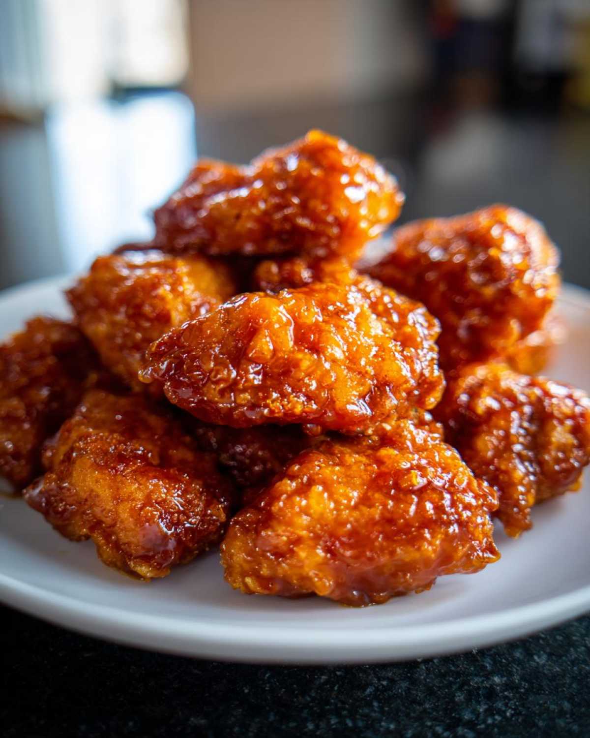 A close-up pile of crispy, glazed chicken pieces coated in a thick, shiny sauce, representing Sticky Orange Chicken Better Than Takeout.