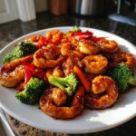 Close-up of glistening Sticky Teriyaki Shrimp Stir Fry Quick Meal with broccoli and red peppers on a white plate.