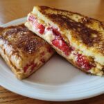 Close-up of Strawberry Cream Cheese Stuffed French Toast, cut in half to show the filling.