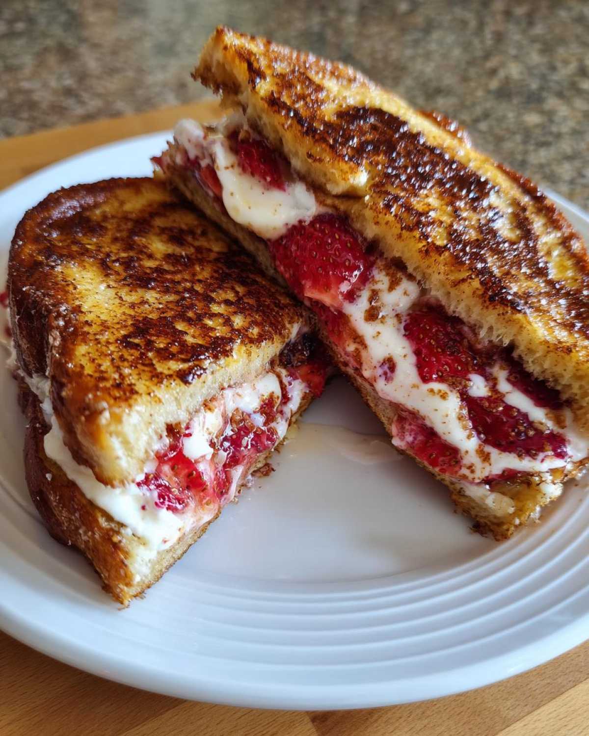 Close-up of Strawberry Cream Cheese Stuffed French Toast cut in half, revealing creamy filling and strawberries.